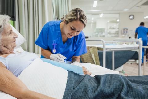 nurse caring for older woman bedside